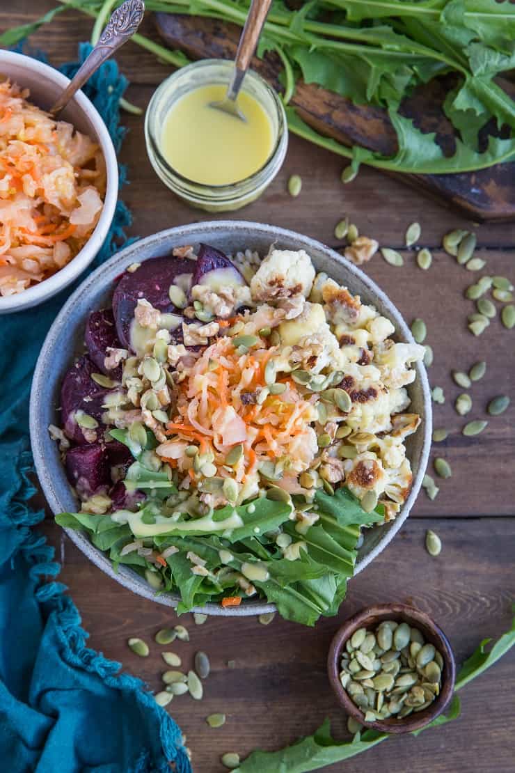 Gut Healthy Probiotic Power Bowls with roasted beets, cauliflower, dandelion greens, brown rice, sauerkraut, and orange dressing. These nutrient-rich bowls are amazing for maintaining a healthy gut.