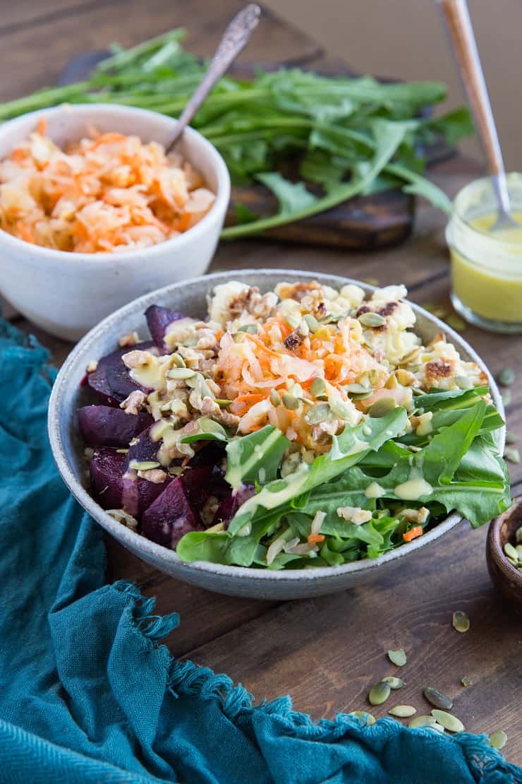 Gut Healthy Probiotic Power Bowls with roasted beets, cauliflower, dandelion greens, brown rice, sauerkraut, and orange dressing. These nutrient-rich bowls are amazing for maintaining a healthy gut microbiome.
