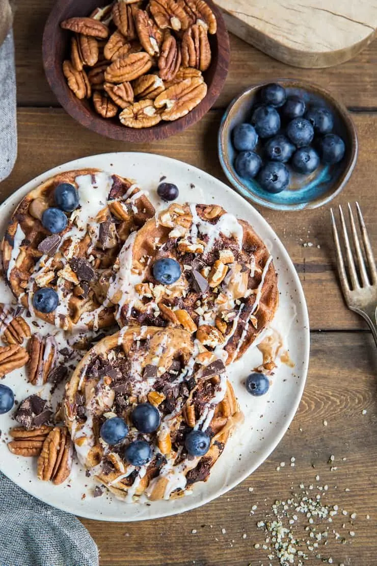 Paleo Chocolate Pecan Waffles with almond butter, coconut butter, and blueberries. This easy waffle recipe is clean and delicious!