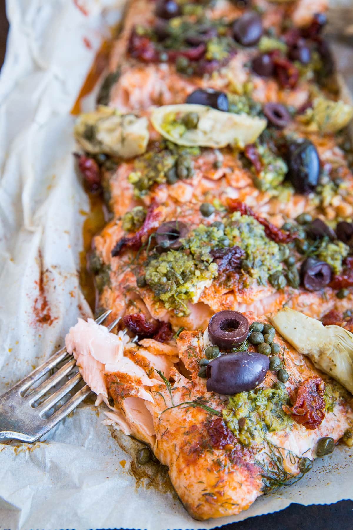 Mediterranean Salmon in Parchment Paper with pesto, sun-dried tomatoes, kalamata olives, artichoke hearts, and capers. An easy, delicious, healthy dinner recipe! #paleo #keto #whole30 #glutenfree #lowcarb