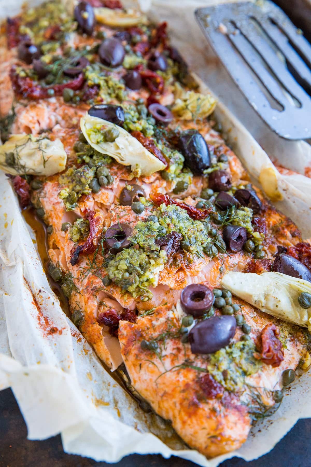 Mediterranean-inspired Salmon in Parchment Paper (or fish en papillote) with sun-dried tomatoes, kalamata olives, dill, capers, and artichoke hearts. This easy dinner recipe is paleo, keto, and packed with flavor!