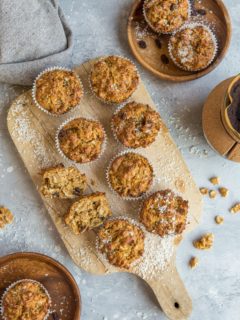 Top down photo of a cutting board of paleo morning glory muffins as well as two wooden plates with muffins on them, ready to eat.