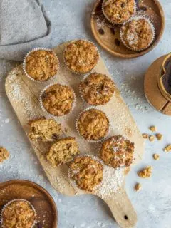Top down photo of a cutting board of paleo morning glory muffins as well as two wooden plates with muffins on them, ready to eat.