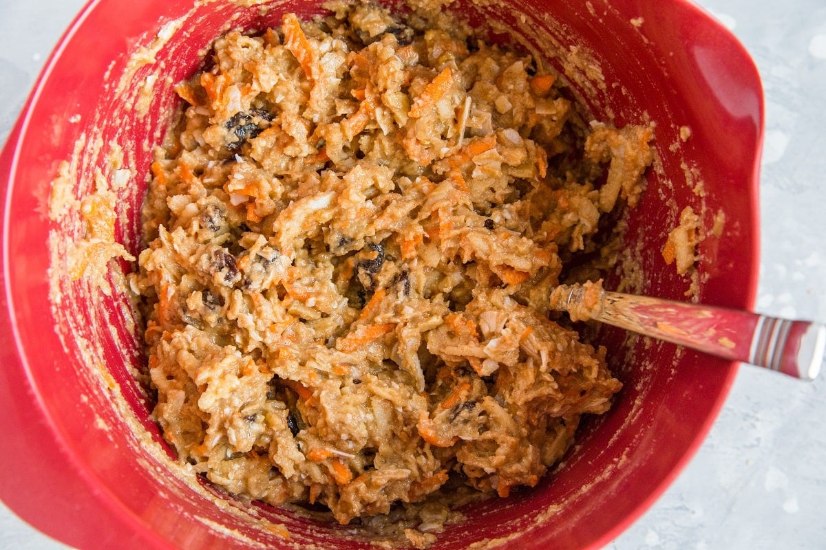 Red mixing bowl of morning glory muffin batter, ready to be turned into muffins.