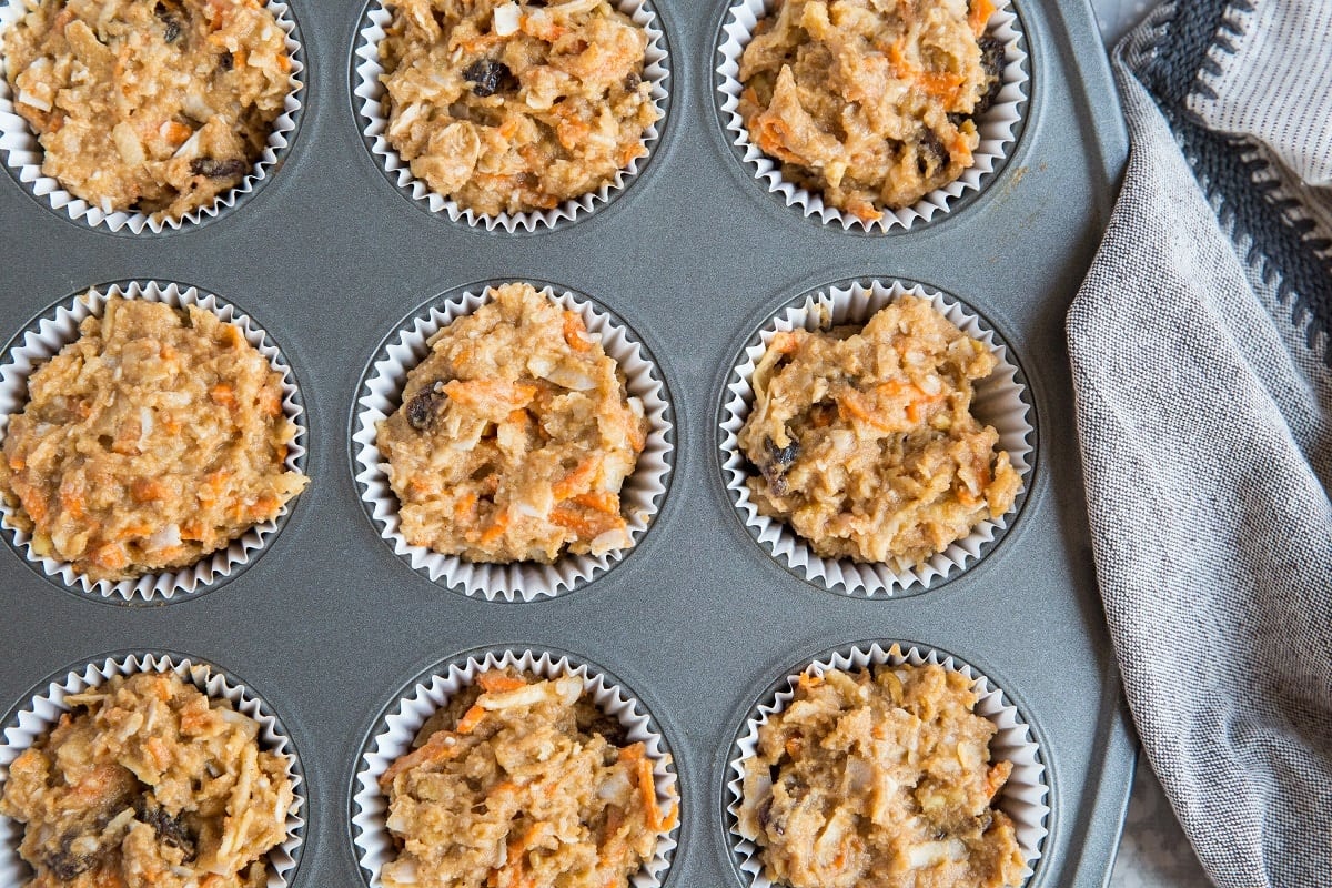 Muffin tray with morning glory muffin batter inside the holes, ready to go into the oven.