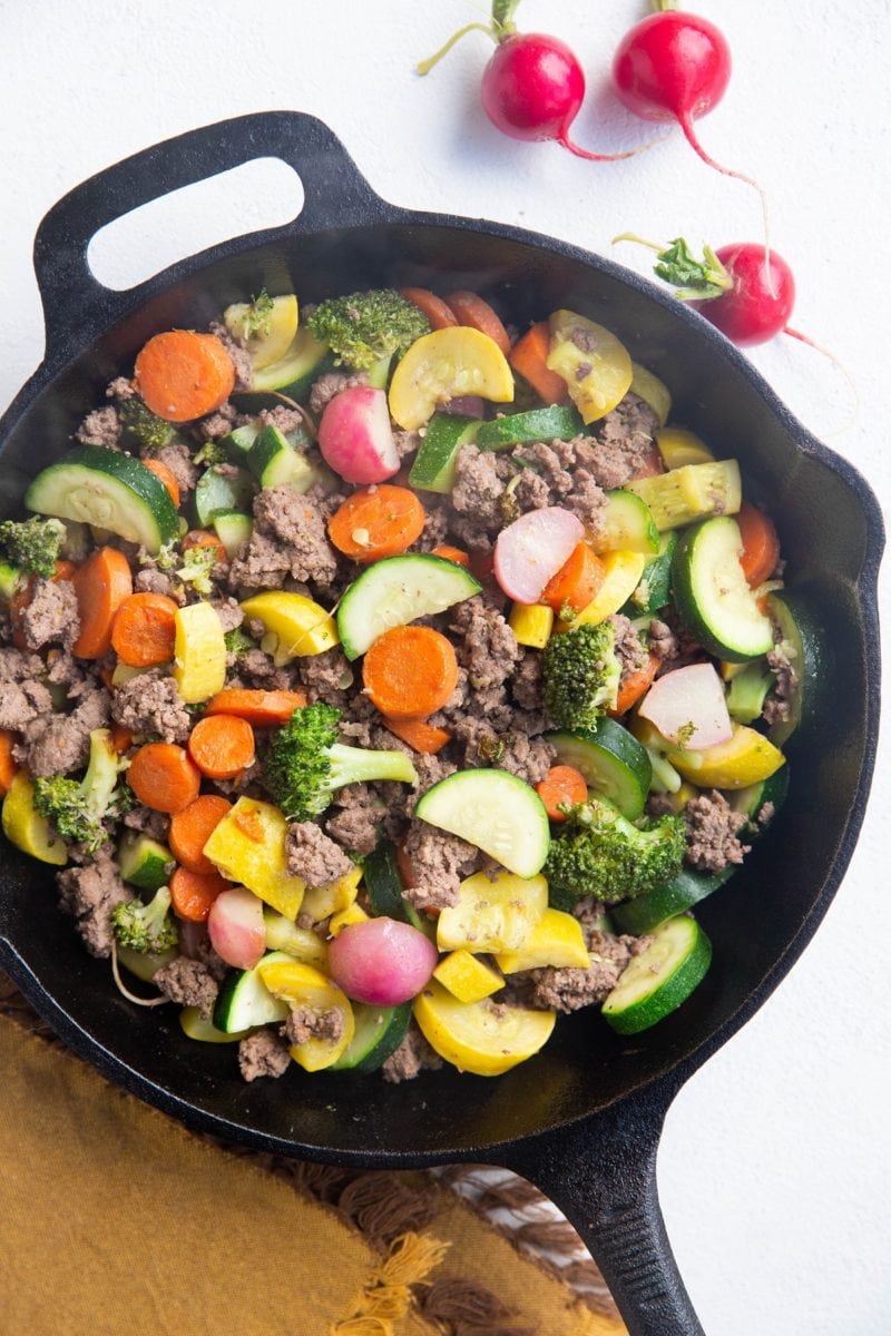 Skillet of beef and vegetables on a white background.