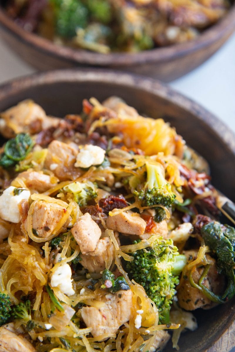 Chicken spaghetti squash with broccoli and sun-dried tomatoes in a wooden bowl. Close up photo on the food.
