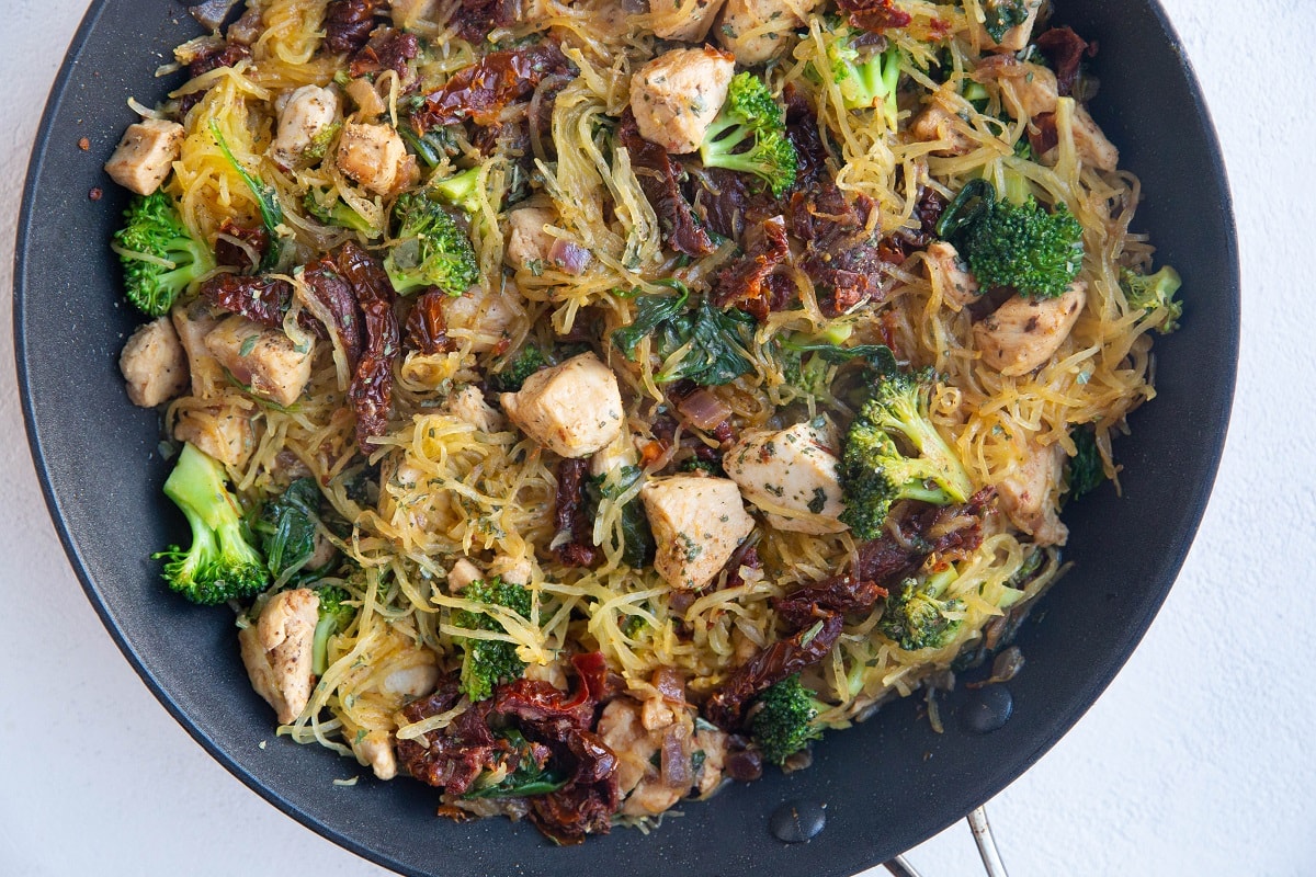 Horiztonal photo of a nonstick skillet of basil chicken spaghetti squash, freshly made.