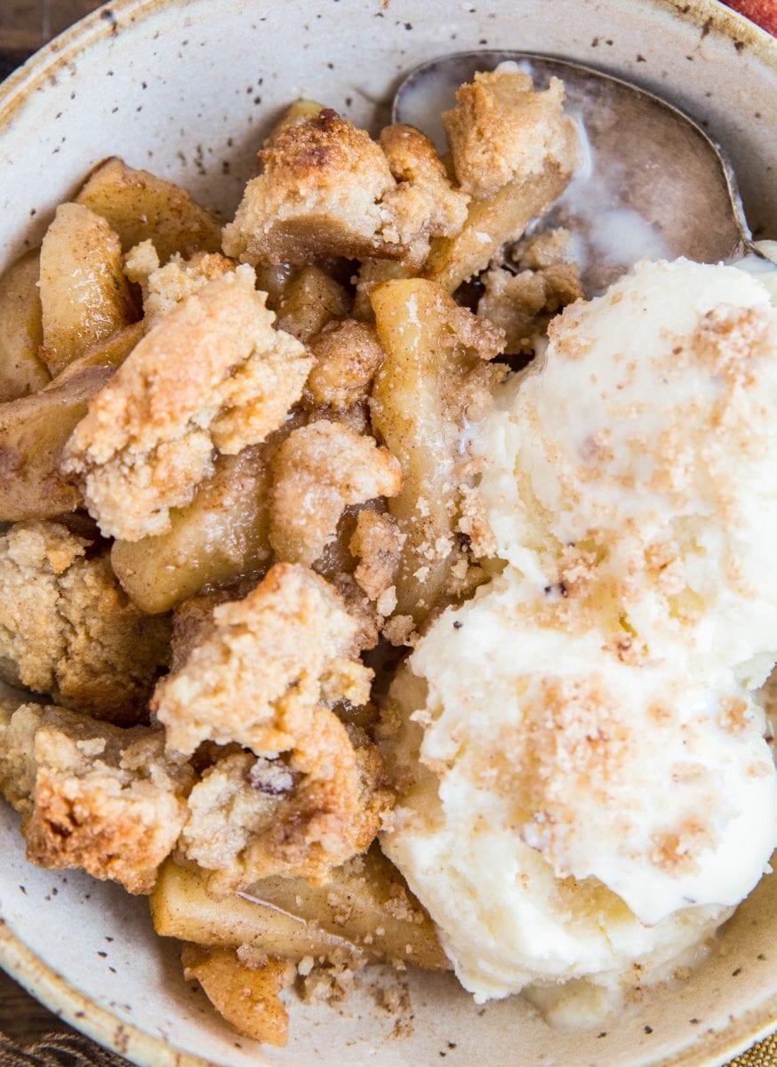Top down image of healthy apple crisp in a bowl with two small scoops of vanilla ice cream