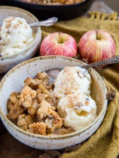 Two bowls of hot apple crisp with scoops of vanilla ice cream