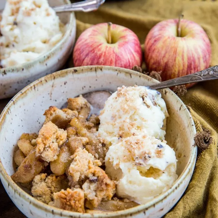 Two bowls of hot apple crisp with scoops of vanilla ice cream