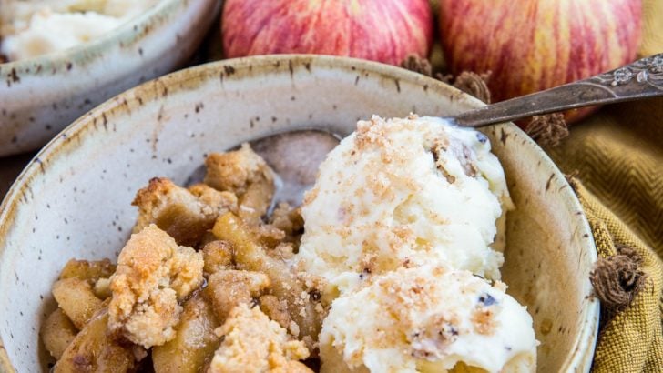 Two bowls of hot apple crisp with scoops of vanilla ice cream