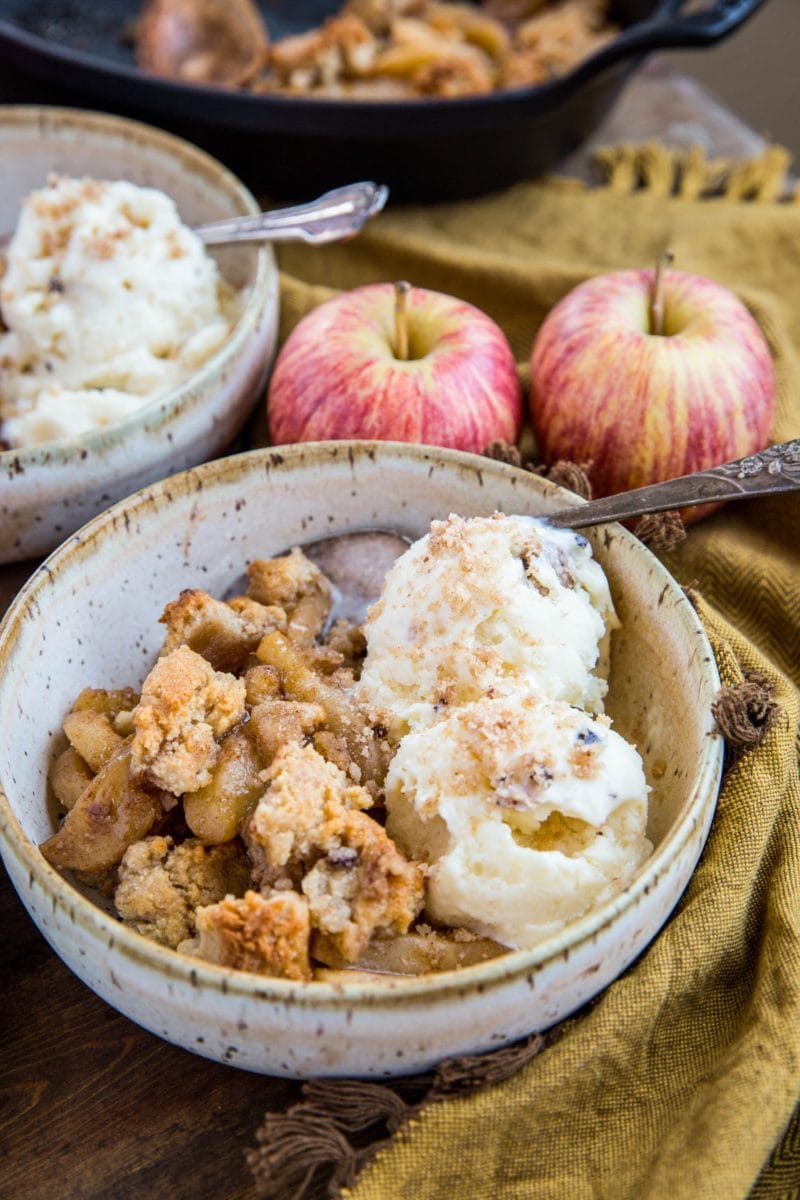 Two bowls of hot apple crisp with scoops of vanilla ice cream