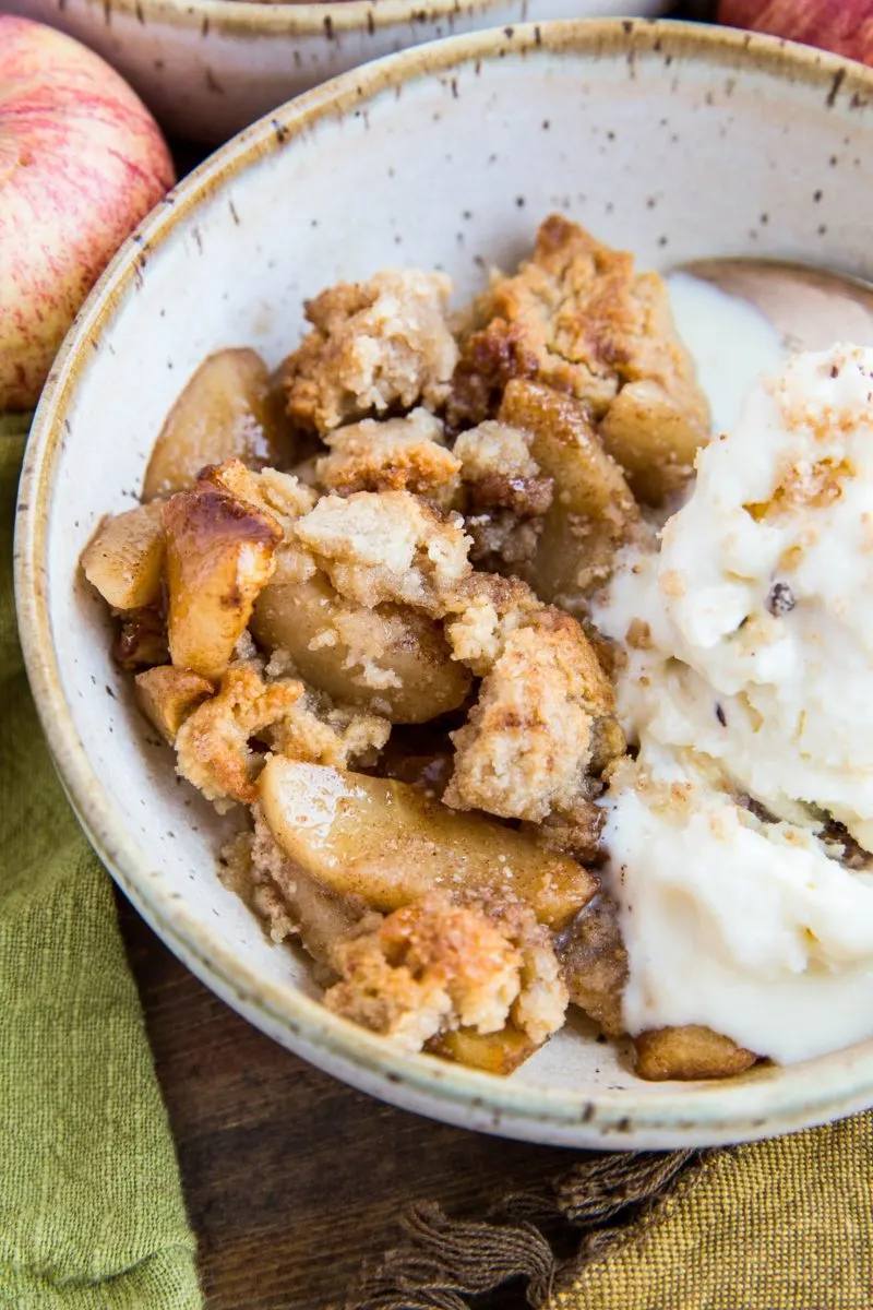 Close up bowl of warm apple crisp with scoops of ice cream.