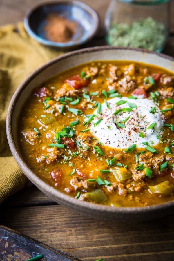 Ceramic bowl of paleo pumpkin chili with yogurt and chives on top.