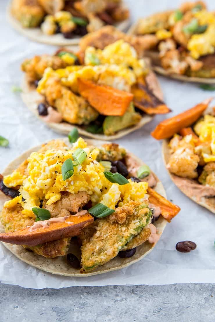 Crispy Avocado Breakfast Tacos with roasted sweet potato, cauliflower, black beans, eggs, and chipotle sauce. A healthy brunch recipe | TheRoastedRoot.net #glutenfree #breakfast