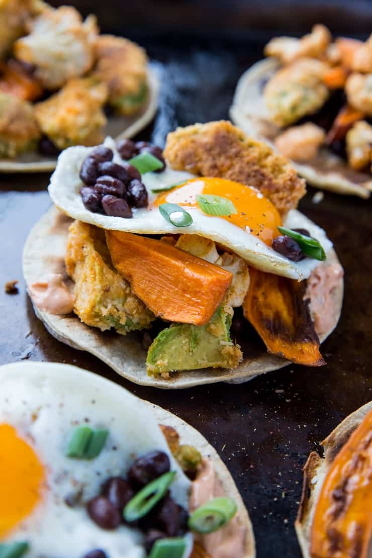 Crispy Avocado Breakfast Tacos with roasted sweet potato, cauliflower, black beans, eggs, and chipotle sauce. A healthy brunch recipe | TheRoastedRoot.net #glutenfree #breakfast