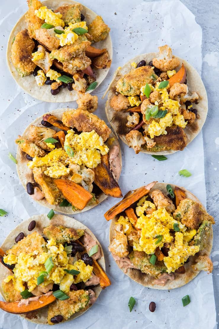 Crispy Avocado Breakfast Tacos with roasted sweet potato, cauliflower, black beans, eggs, and chipotle sauce. A healthy brunch recipe | TheRoastedRoot.net #glutenfree #breakfast