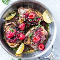 top down photo of balsamic raspberry jam chicken with raspberry jam to the side and sprigs of parsley