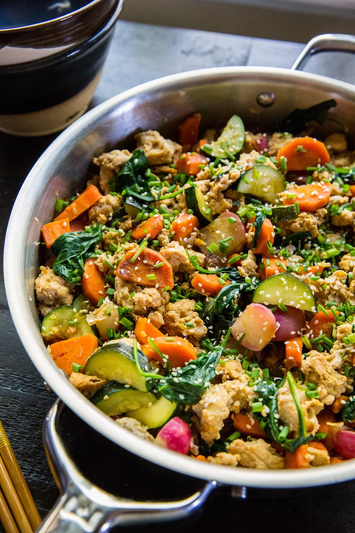 Stainless steel skillet at an angle, filled with ground turkey and vegetables.