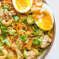 close up egg roll in a bowl with chop sticks to the side.