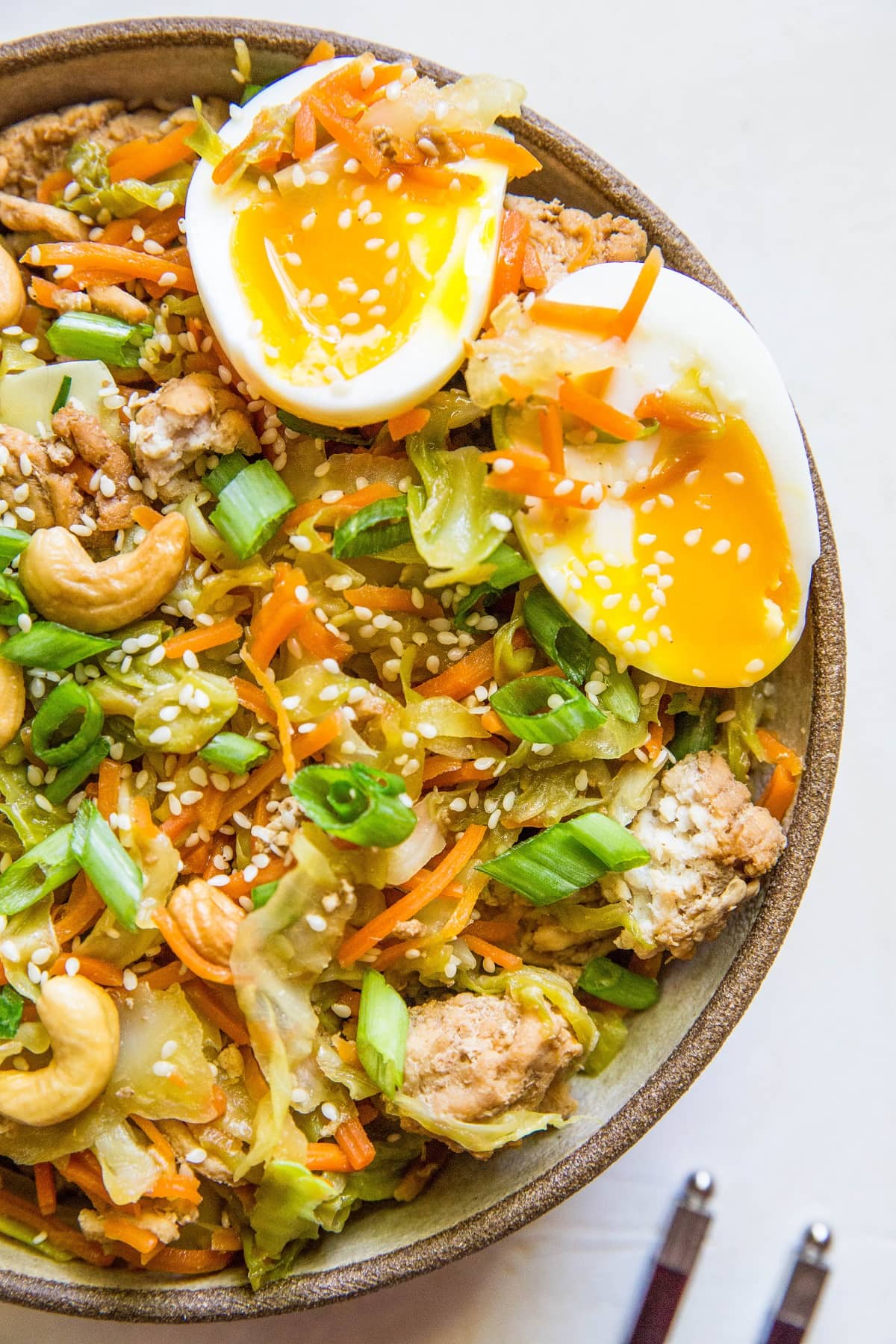 close up egg roll in a bowl with chop sticks to the side.