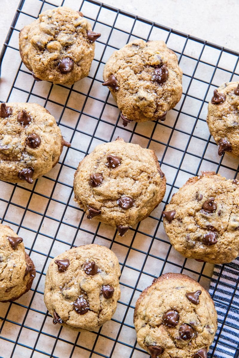 Wire rack with gluten-free chocolate chip cookies on it and a blue striped napkin underneath.