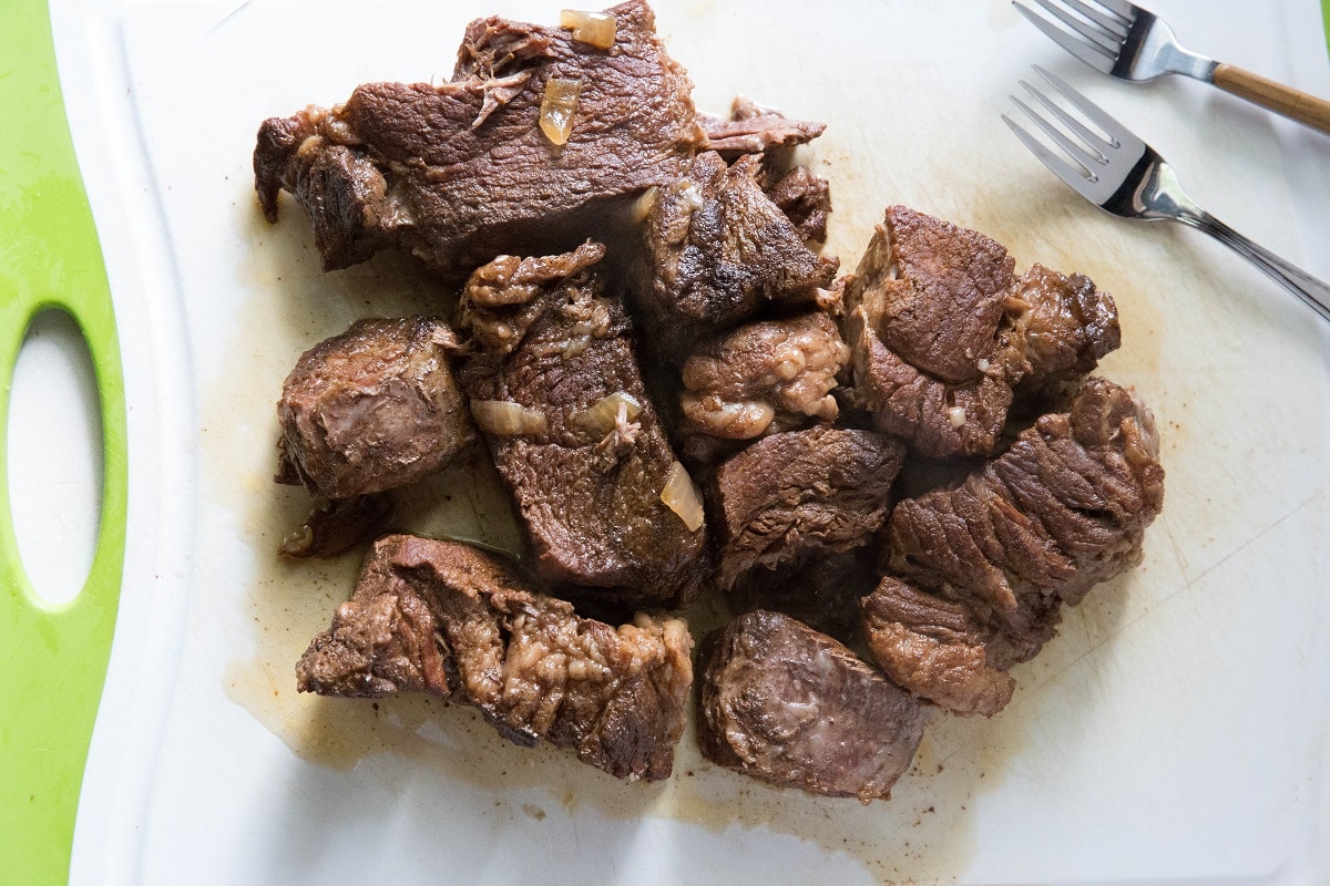 Chunks of beef on a cutting board waiting to be shredded