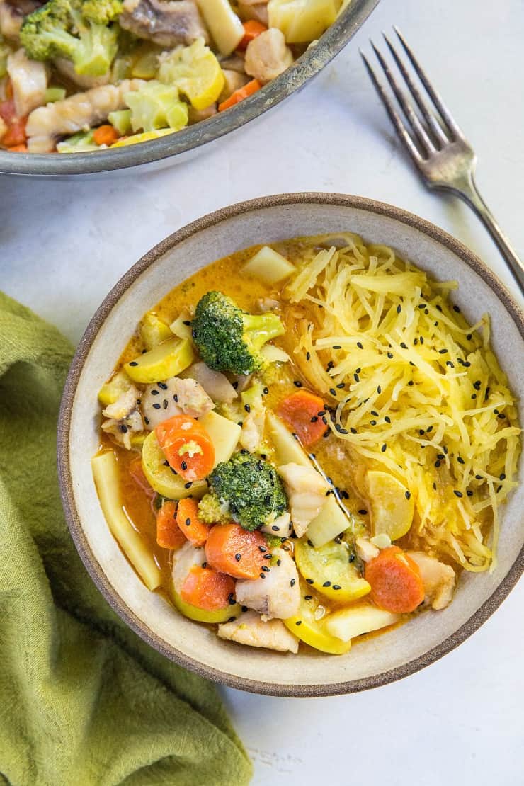 bowl of thai red curry served with spaghetti squash with a fork next to it and a napkin