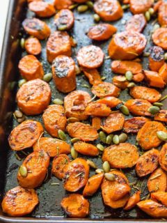 roasted carrots on a baking sheet with pumpkin seeds
