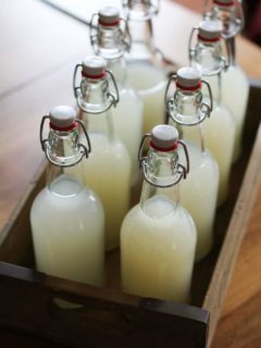 Wooden serving tray with eight bottles of ginger beer inside on a wood table