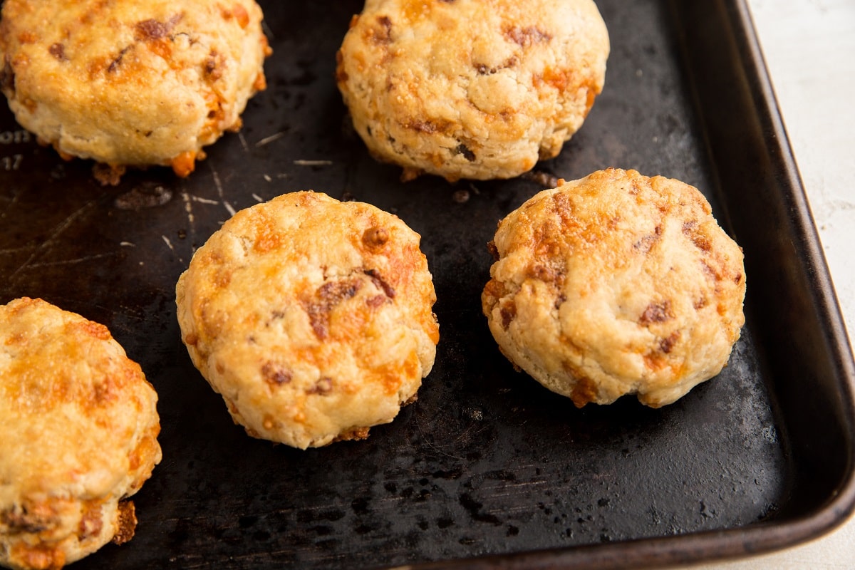 Batch of gluten-free bacon cheddar biscuits on a sheet pan fresh out of the oven