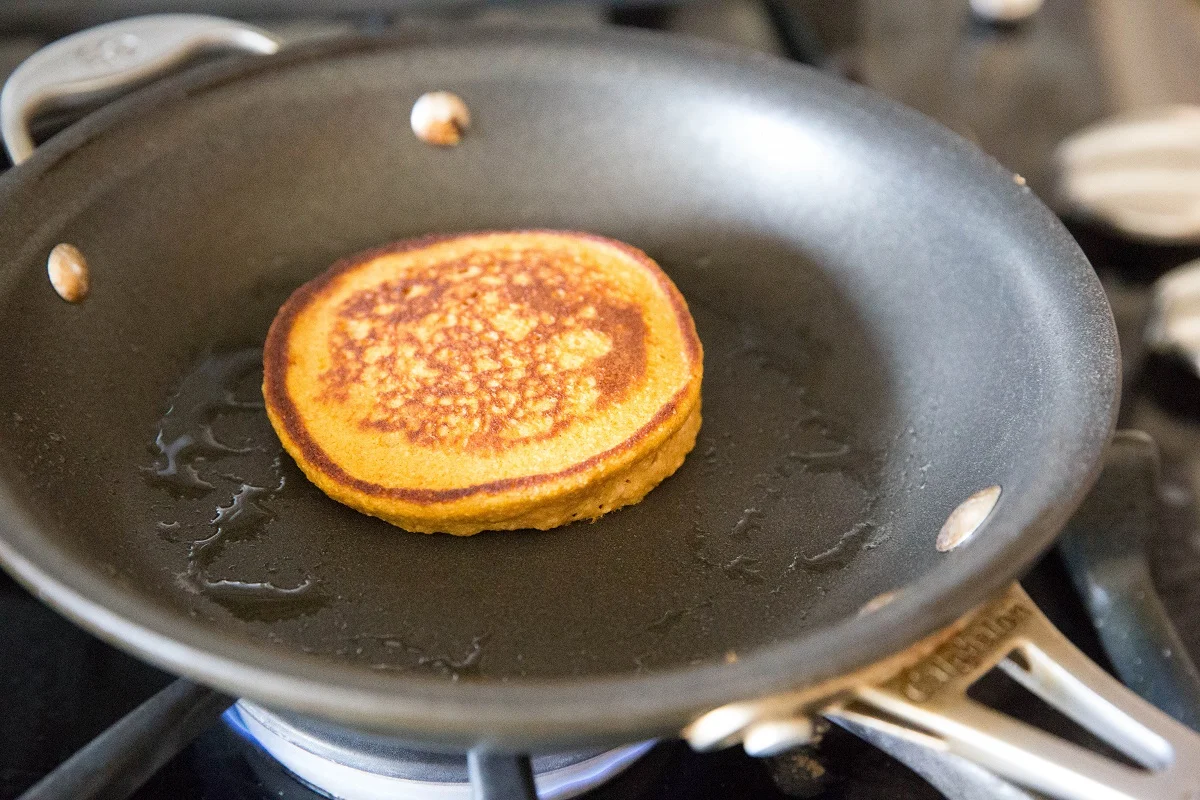 Sweet potato pancake cooking in a skillet on the stove top