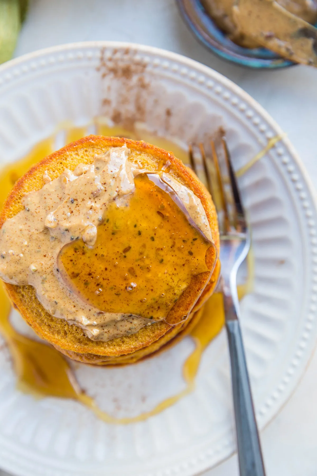 top down photo of sweet potato pancakes with almond butter and honey on top