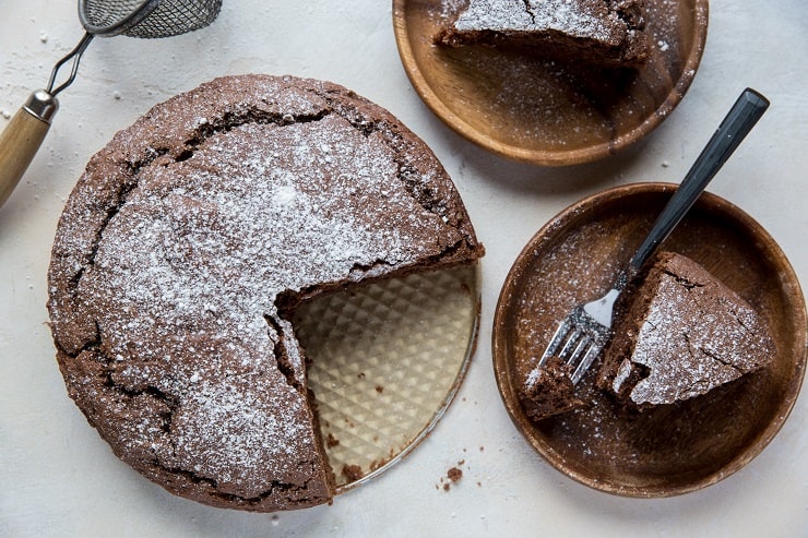 gluten-free chocolate cake with two slices taken out on wooden plates