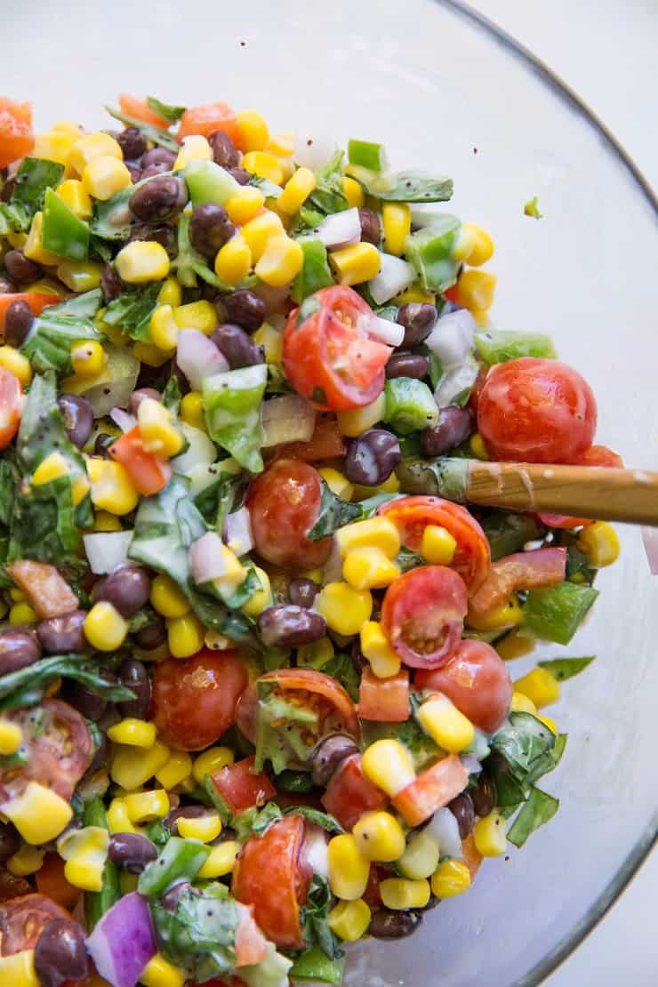 Black Bean Corn Salad with fresh vegetables and poppy seed dressing in a mixing bowl