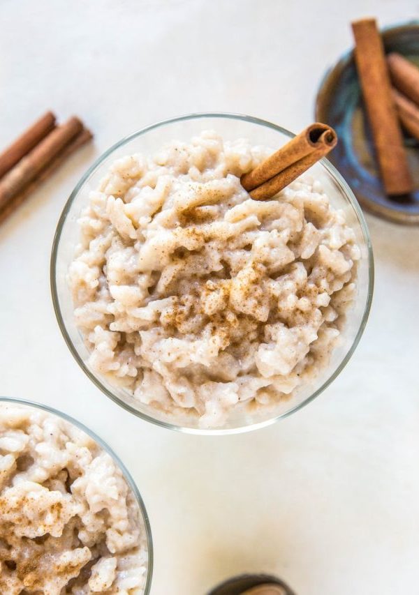 Two desserts bowls of rice pudding with a napkin and spoons to the side.
