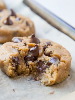 Close up of a peanut butter chocolate chip cookie with a bite taken out with gooey chocolate visible.