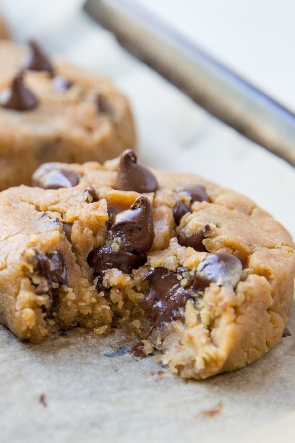 Close up of a peanut butter chocolate chip cookie with a bite taken out with gooey chocolate visible.