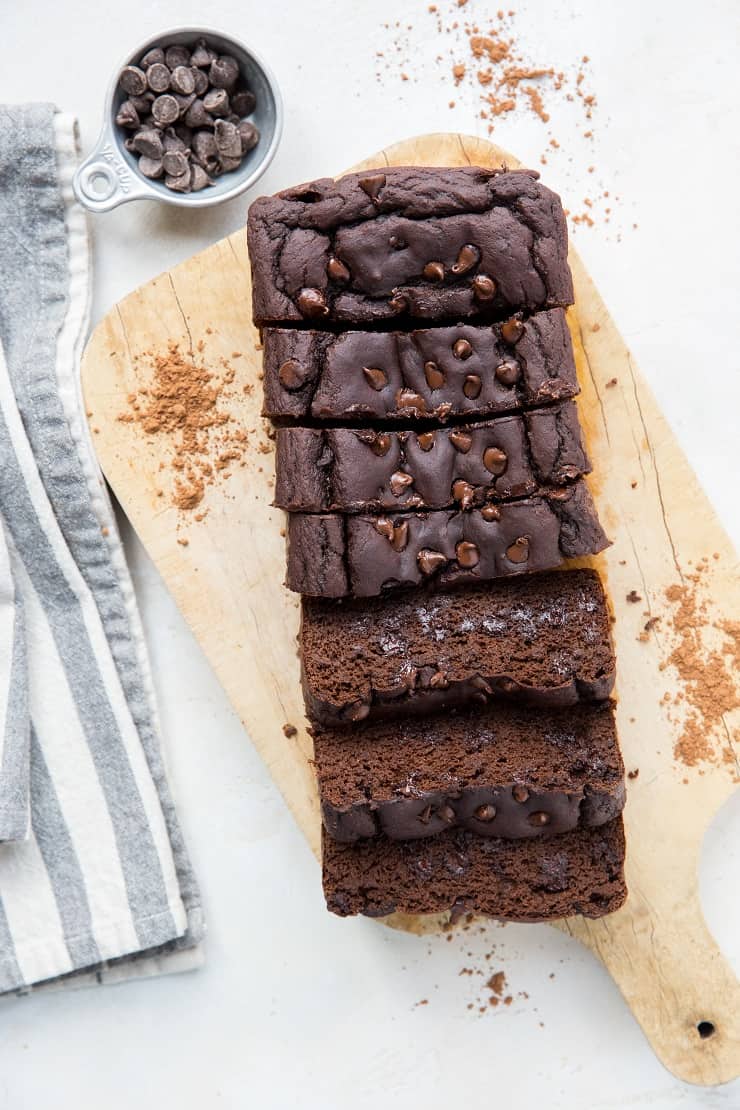 loaf of black bean banana bread on a wooden cutting board with a blue striped napkin