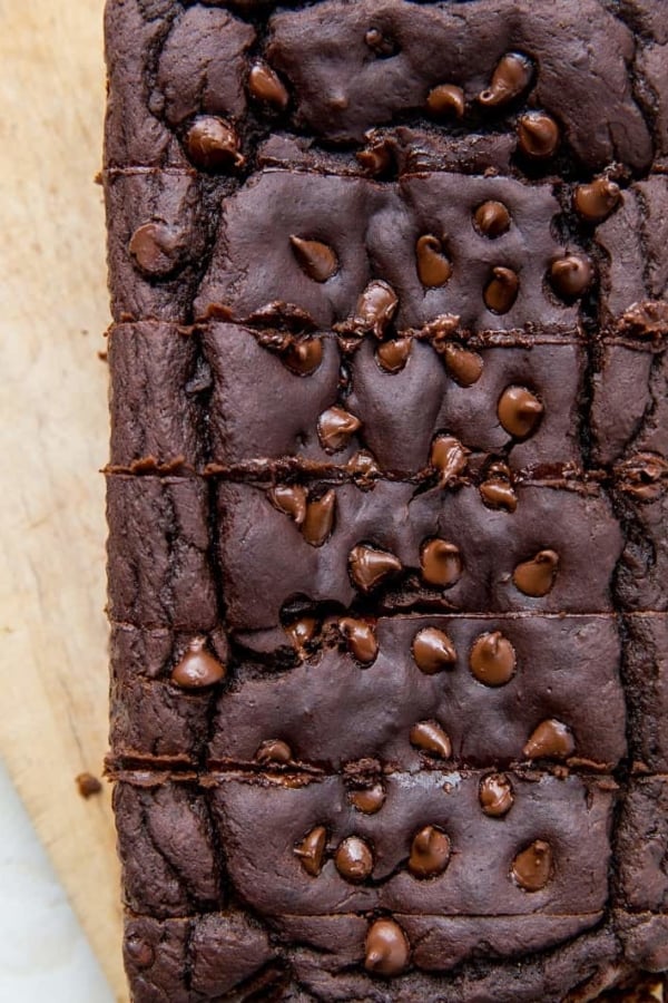 Top down photo of chocolate black bean banana bread on parchment paper with slices cut