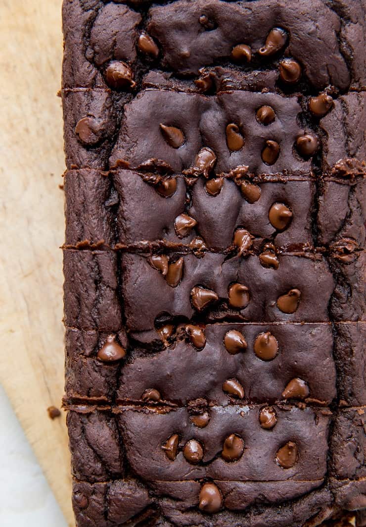 Top down photo of chocolate black bean banana bread on parchment paper with slices cut