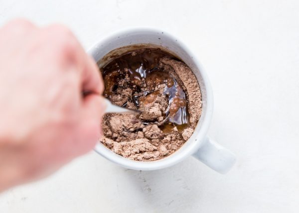 Hand stirring the wet ingredients into the brownie mix.