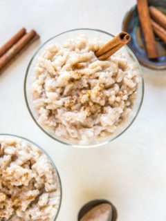 Two desserts bowls of rice pudding with a napkin and spoons to the side.