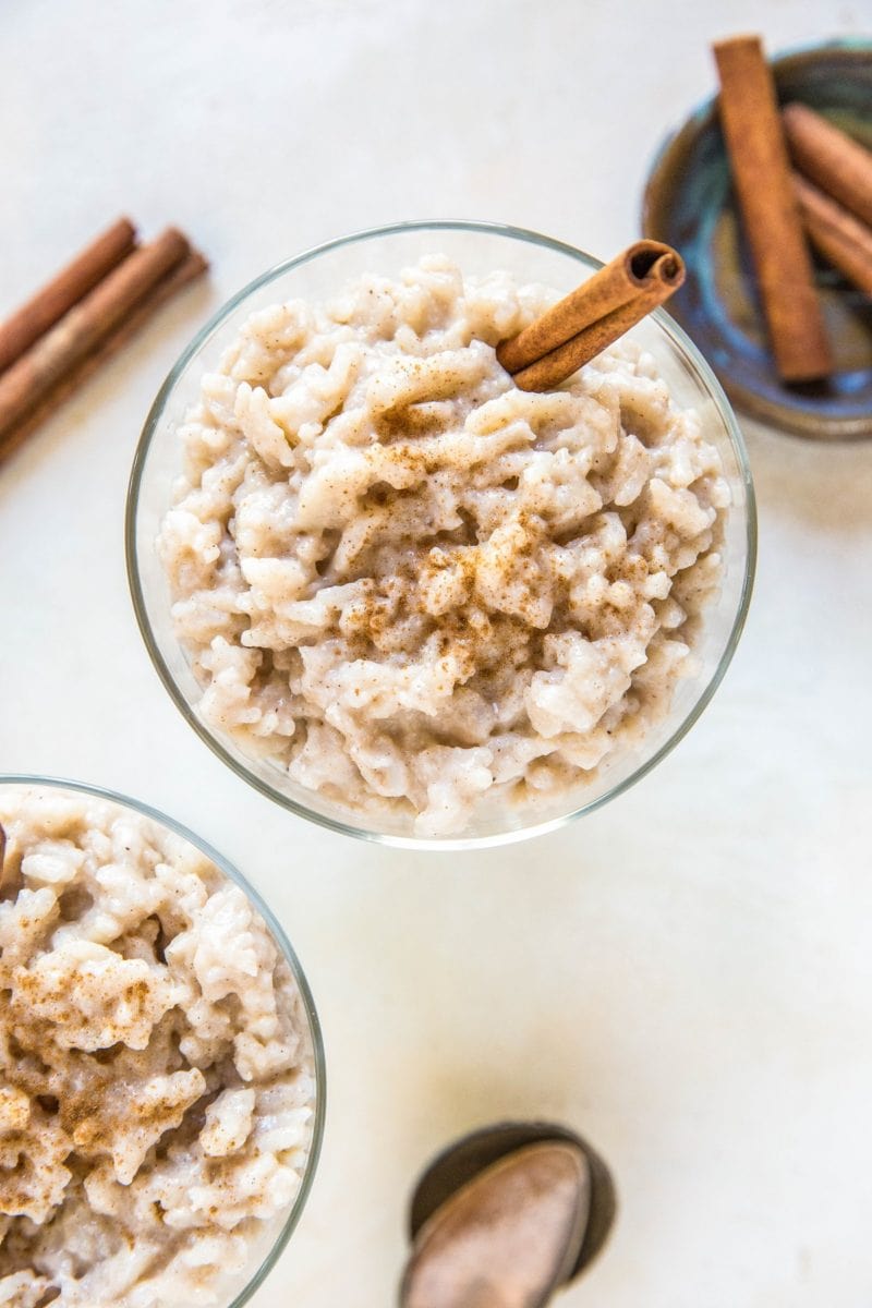 Two desserts bowls of rice pudding with a napkin and spoons to the side.