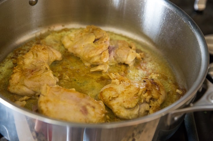 Browning turmeric chicken thighs in a skillet