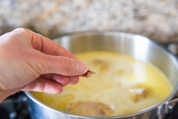 Adding saffron to skillet of turmeric marinated chicken