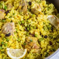 Aromatic Saffron Chicken with Coconut Rice in a large skillet with slices of lemon