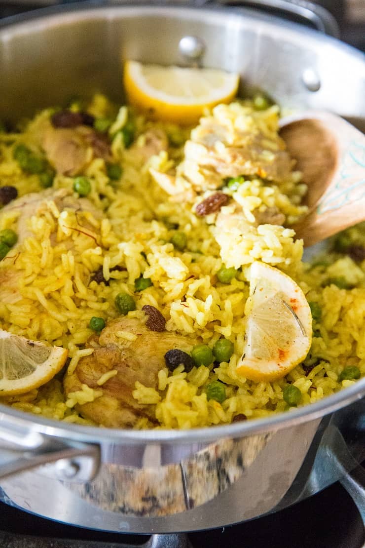 Finished saffron chicken and coconut rice in a skillet on a stove top