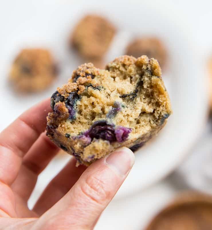 Hand holding a muffin with bite taken out